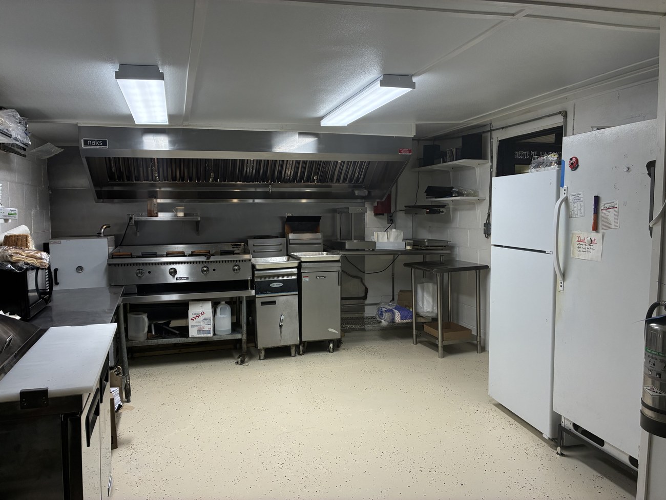 Commercial kitchen with grill, fryers, and hood
